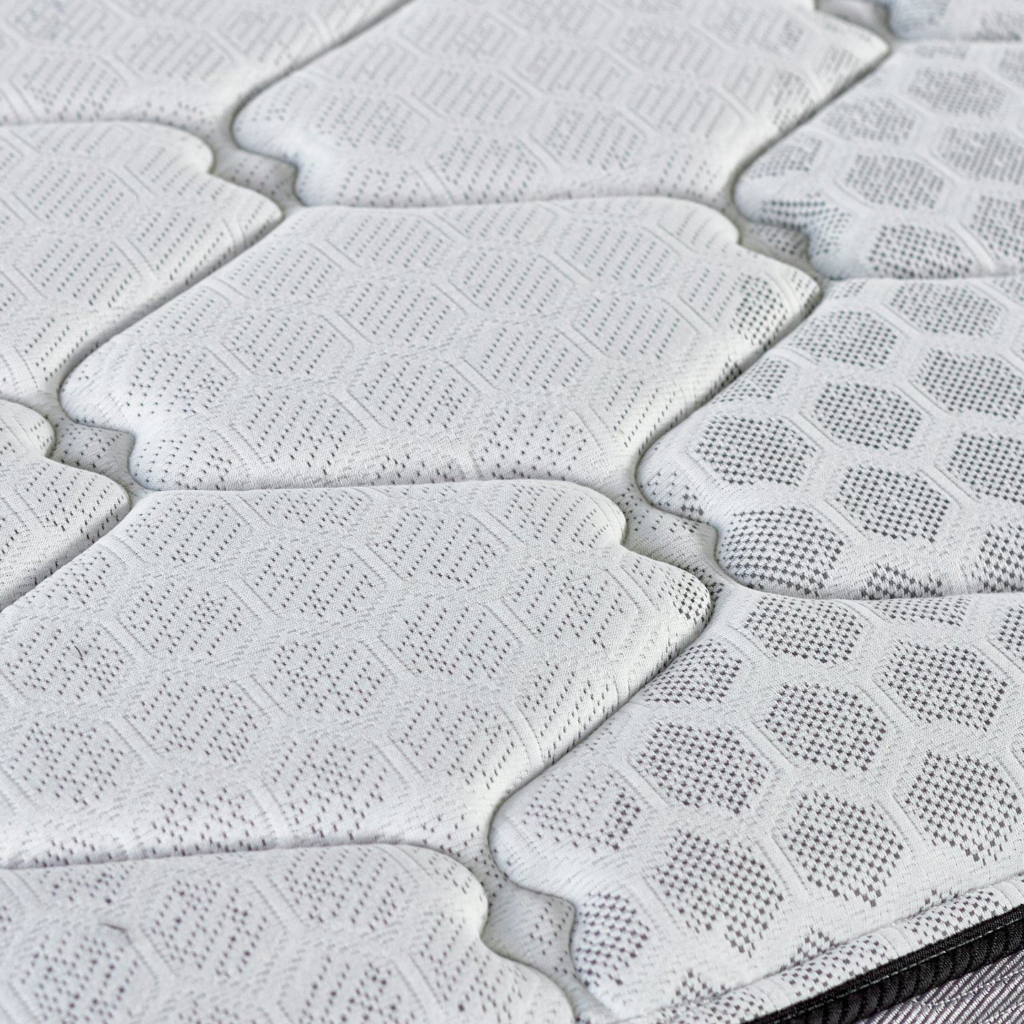 Close up of a mattress with quilted diamond and hexagonal patterns.